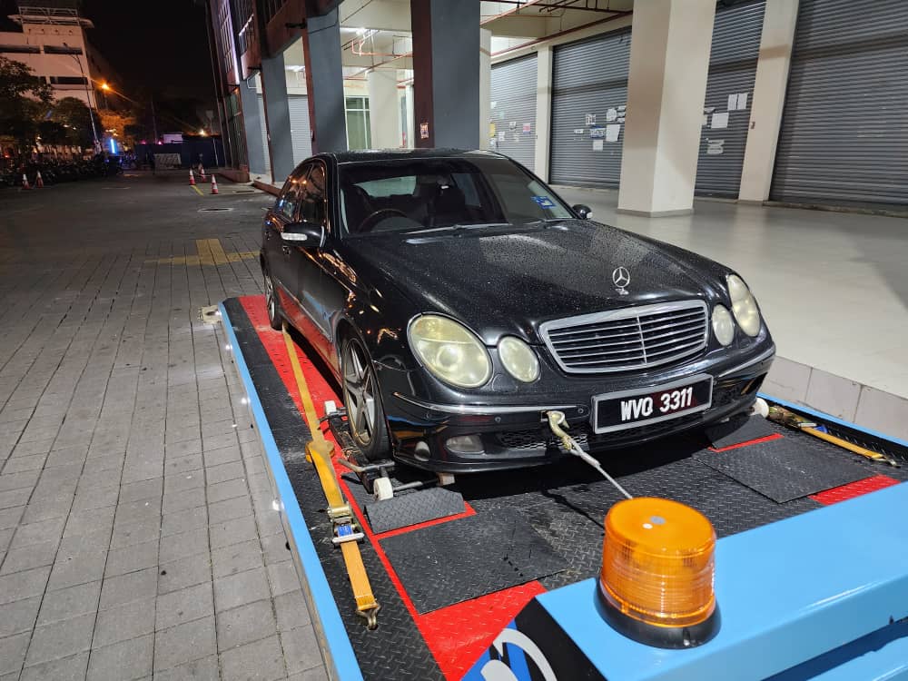 Black Mercedes secured on a 47 Towing flatbed at night